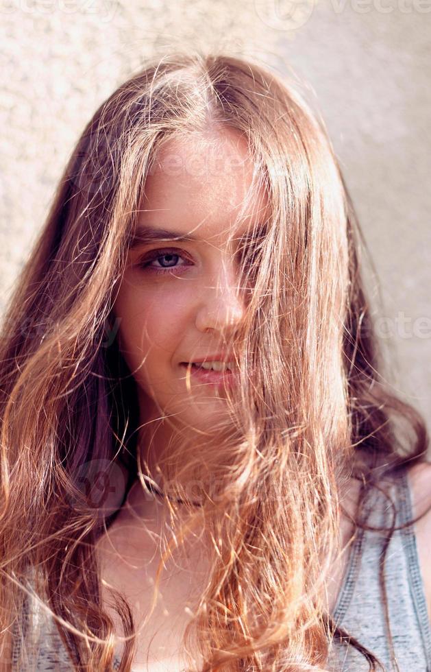 menina de cabelo comprido se desenvolvendo ao vento e iluminada pelos raios do sol foto