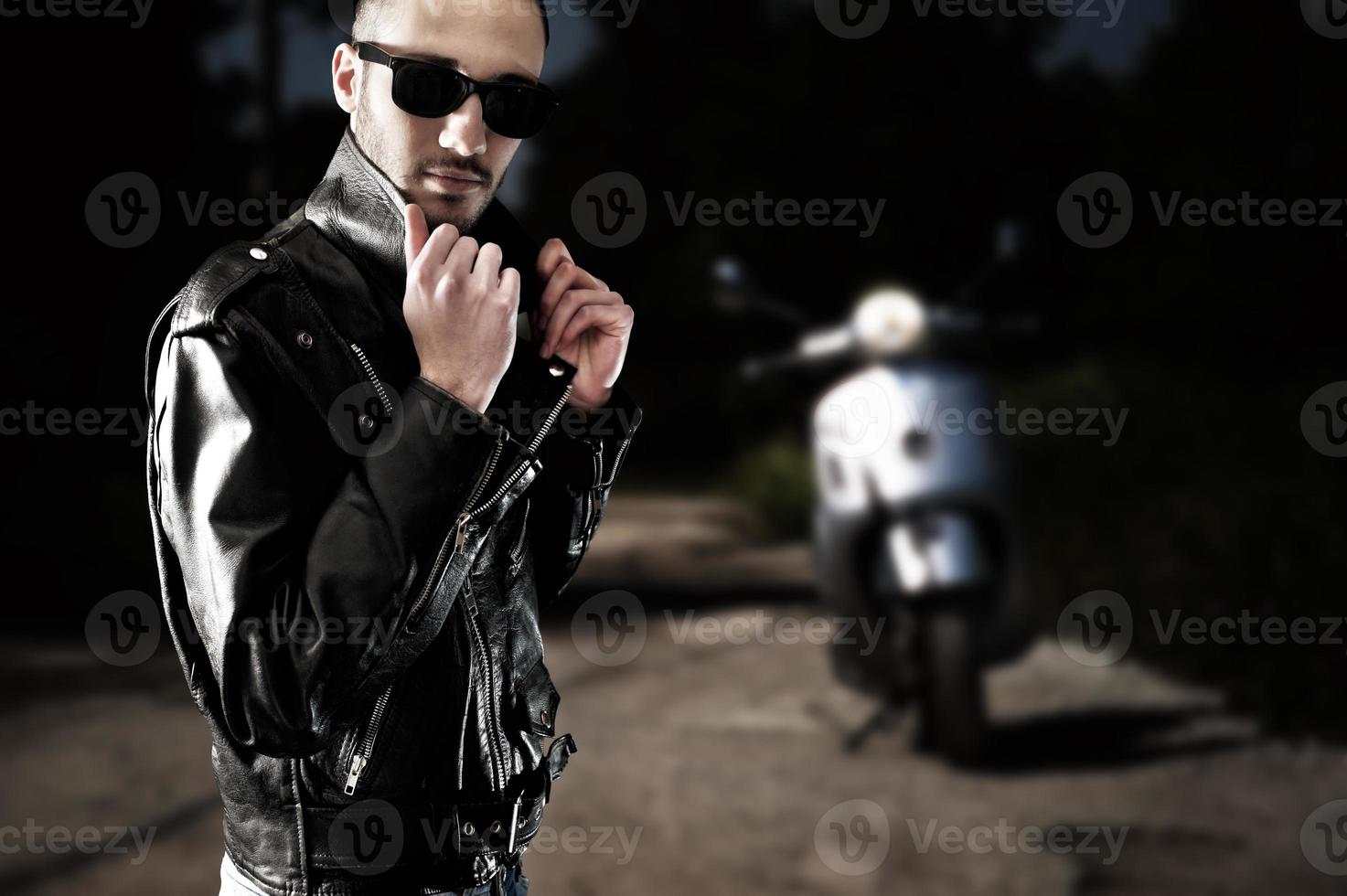 motociclista em jaqueta de couro e óculos escuros foto