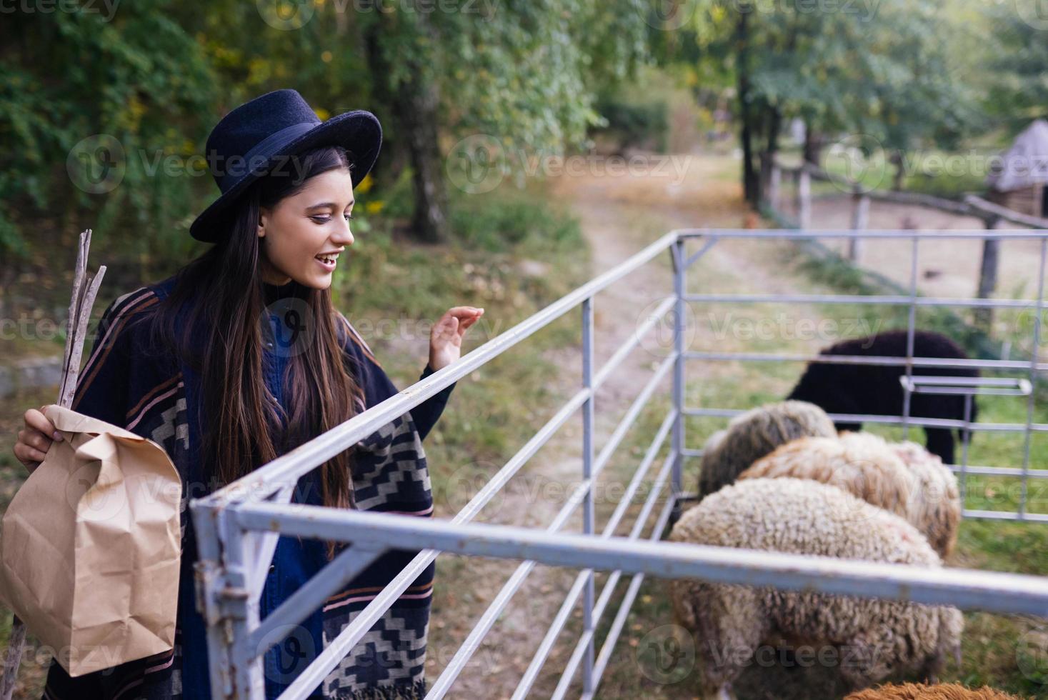 jovem mulher perto de um curral com ovelhas em uma fazenda foto