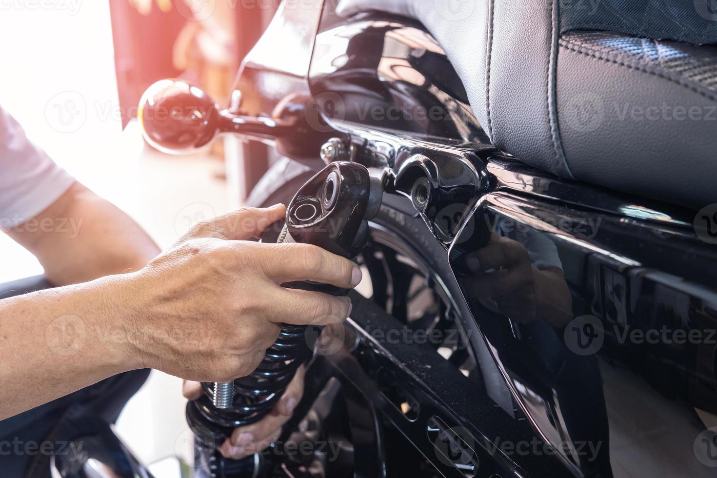 mecânico de motocicleta verificar e trocar amortecedores traseiros scooter de motocicleta na garagem, conceito de reparo, manutenção e serviço de motocicleta foto