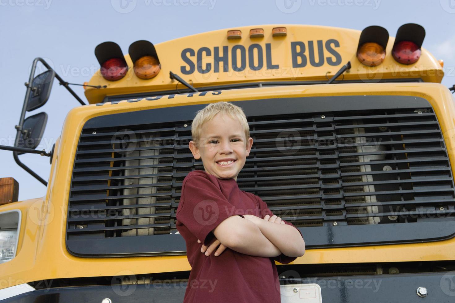 estudante do ensino fundamental parado perto do ônibus escolar foto