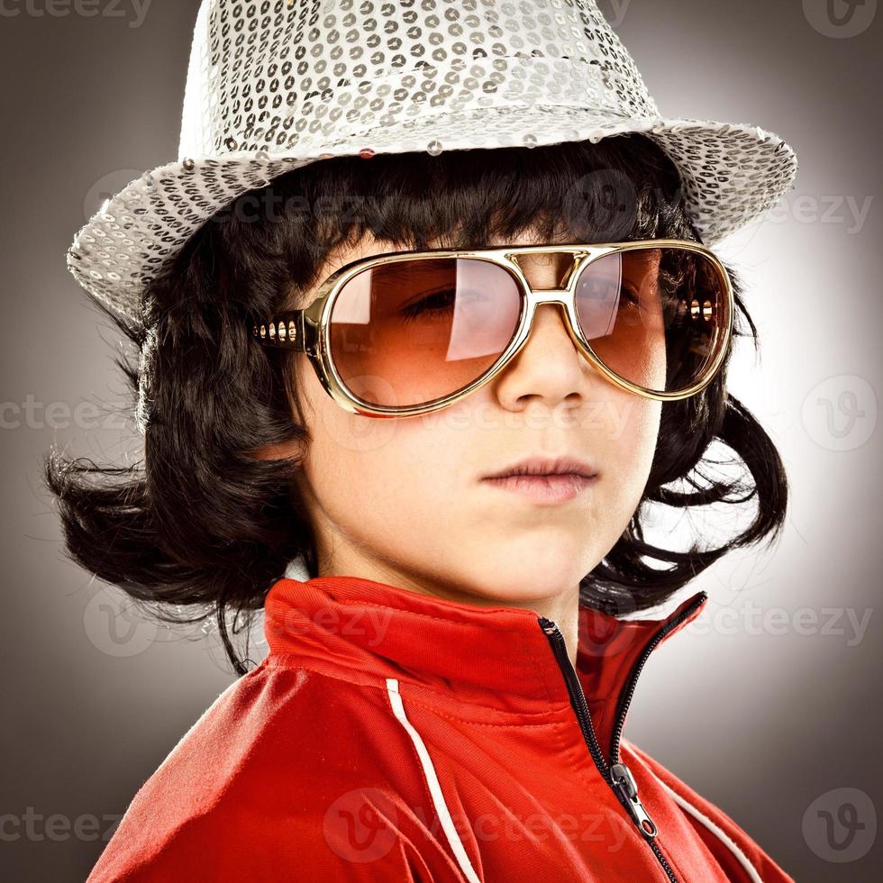 menino discoteca moderno estilo 1970 com óculos escuros e retrato de chapéu foto