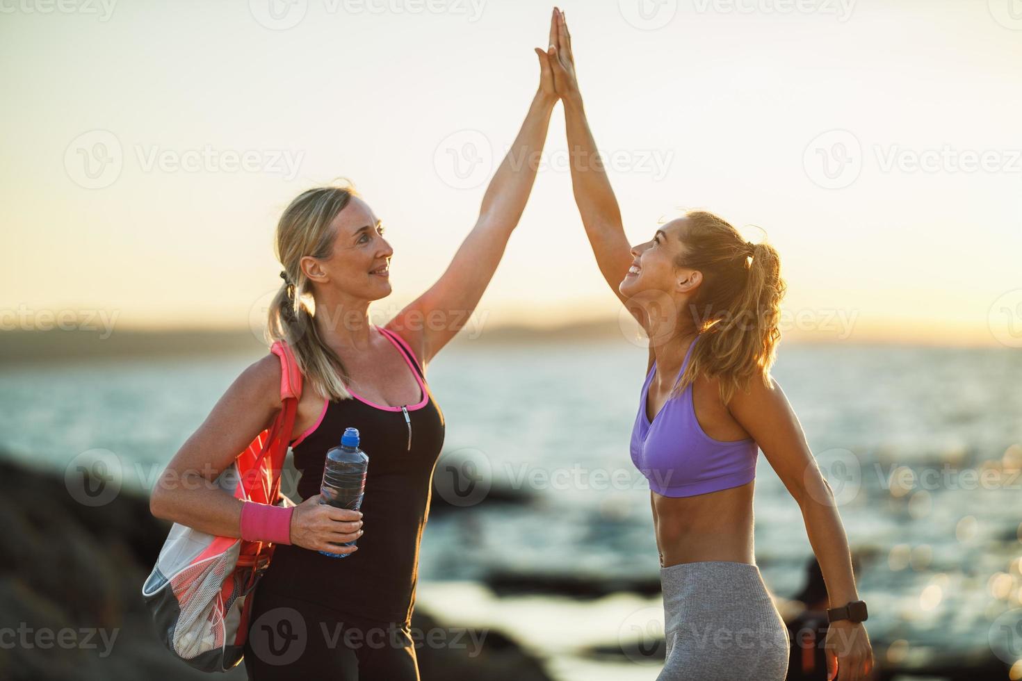 mãe e filha adulta comemoram durante treino ao ar livre perto do mar foto