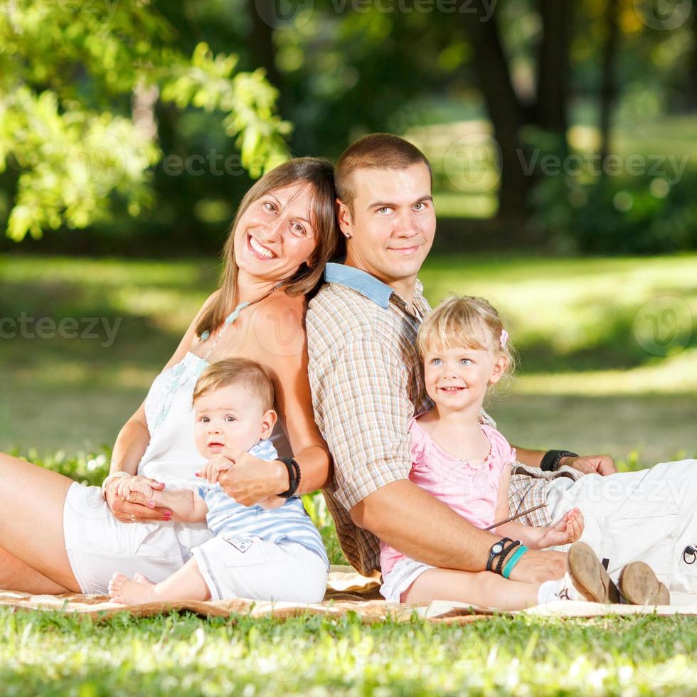 família feliz descansando no parque foto