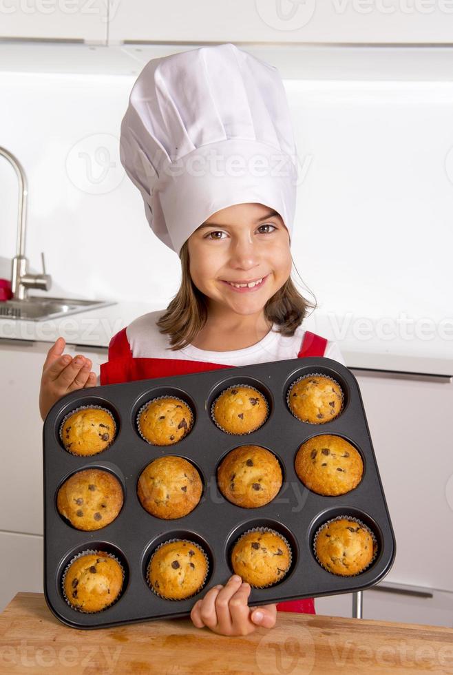 criança orgulhosa e feliz apresentando bolos de muffin e aprendendo a cozinhar foto