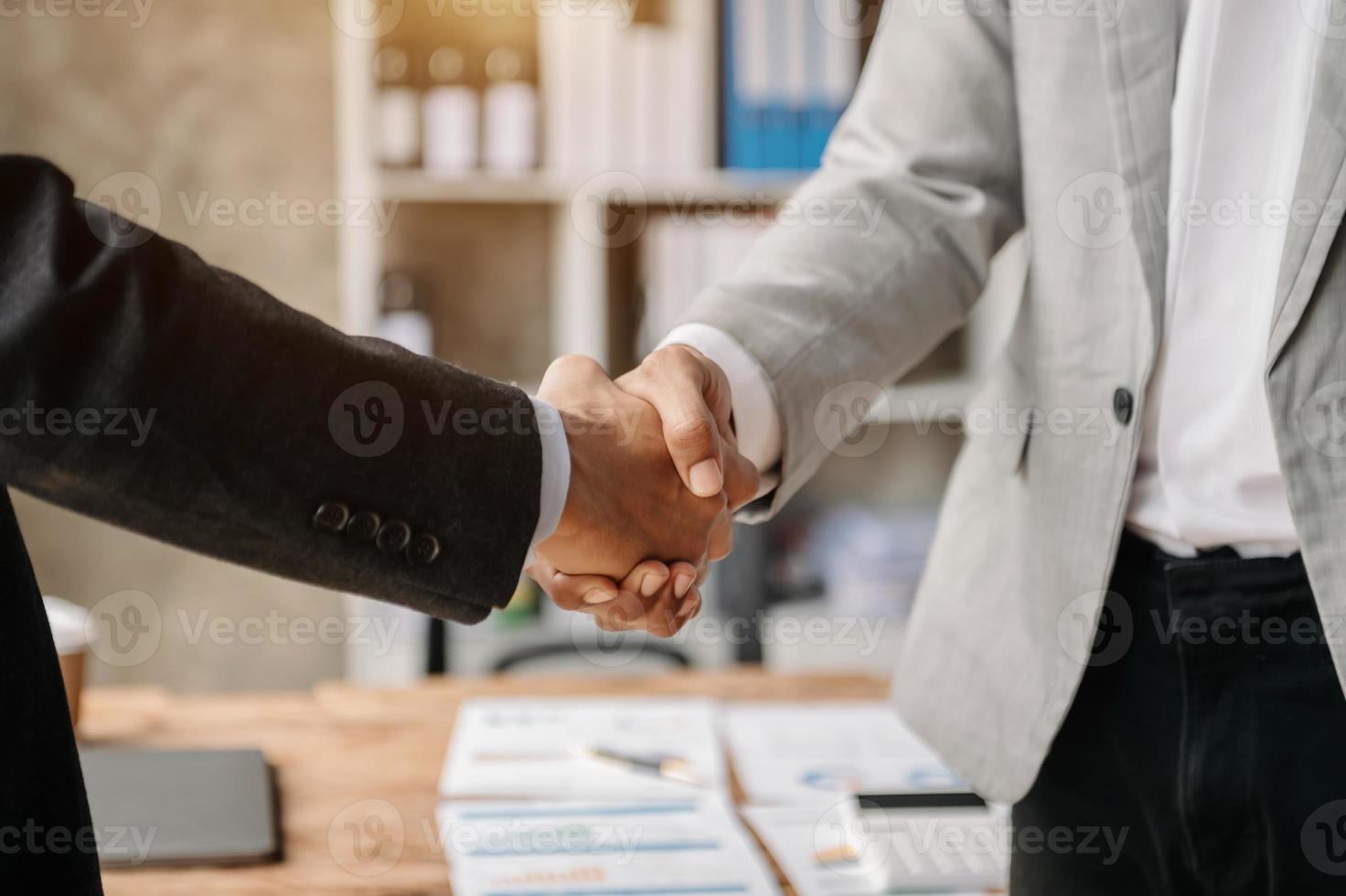 dois homens de negócios confiantes apertando as mãos durante uma reunião no escritório, sucesso, negociação, saudação e parceiro na luz do sol foto