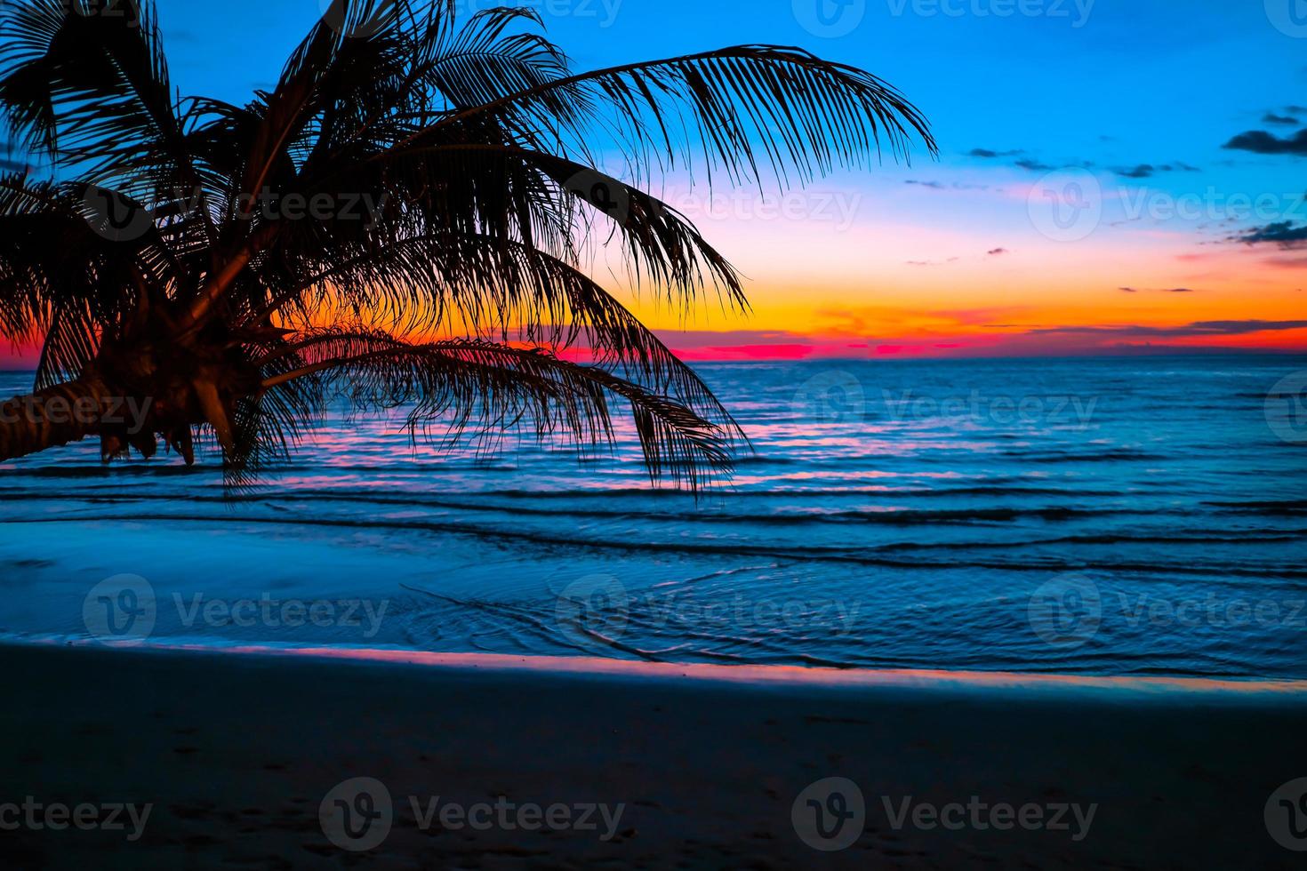 silhueta de palmeiras lindo pôr do sol no fundo da praia do mar tropical para viagens em férias relaxe o tempo foto