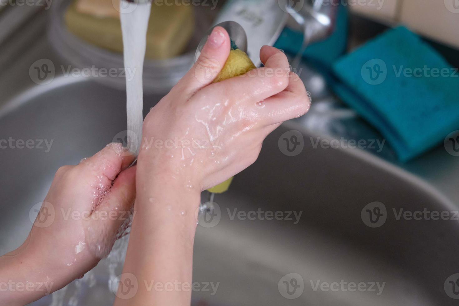 mãos na água lavando prato de pratos foto