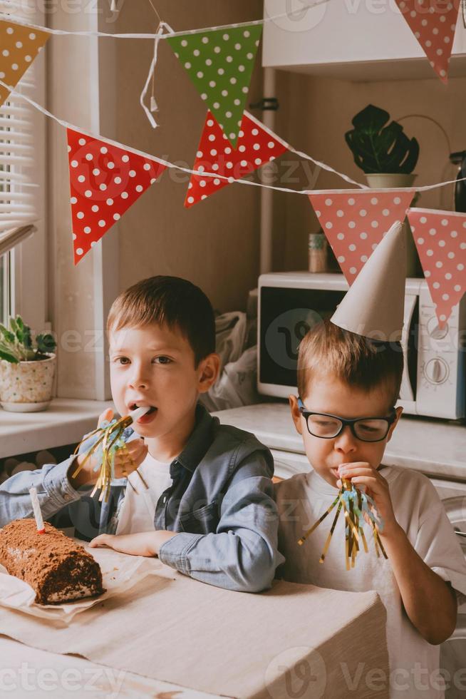 os meninos estão comemorando seu aniversário. parafernália de aniversário infantil. irmãos cobertos de bolo na cara. festa em família em casa foto