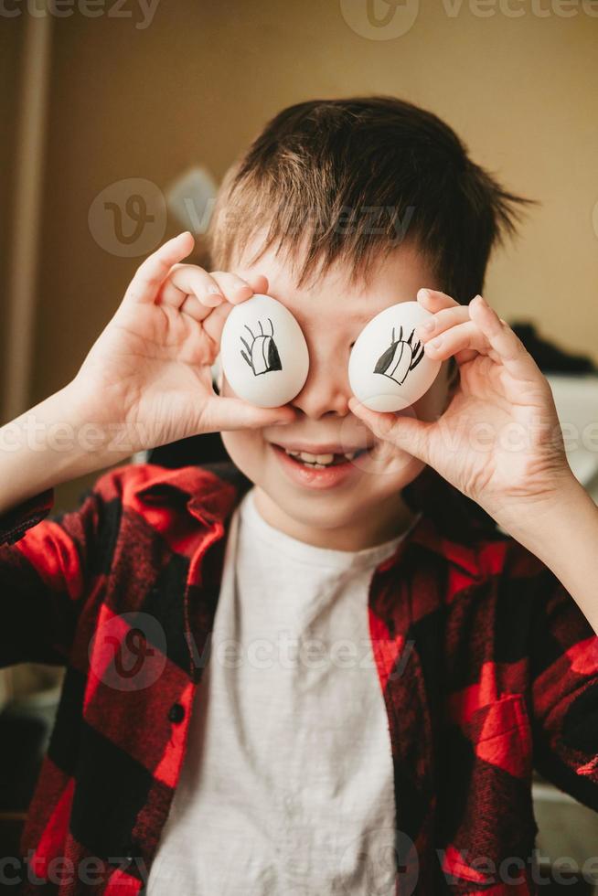 foto engraçada de um menino com ovos em vez de olhos. ovos com olhos pintados. preparando-se para a páscoa. divertido cozinhar com as crianças