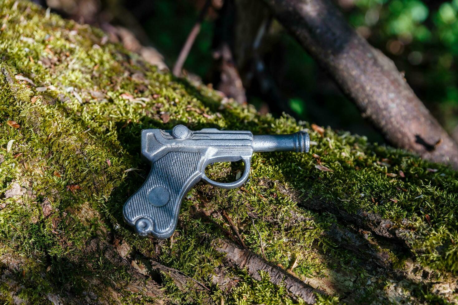 arma de brinquedo feita de chumbo está em uma velha árvore com musgo foto