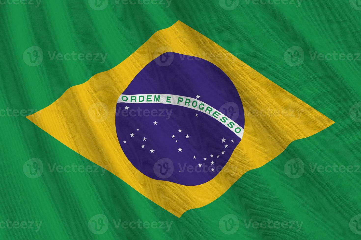 bandeira do brasil com grandes dobras acenando perto sob a luz do estúdio dentro de casa. os símbolos e cores oficiais no banner foto