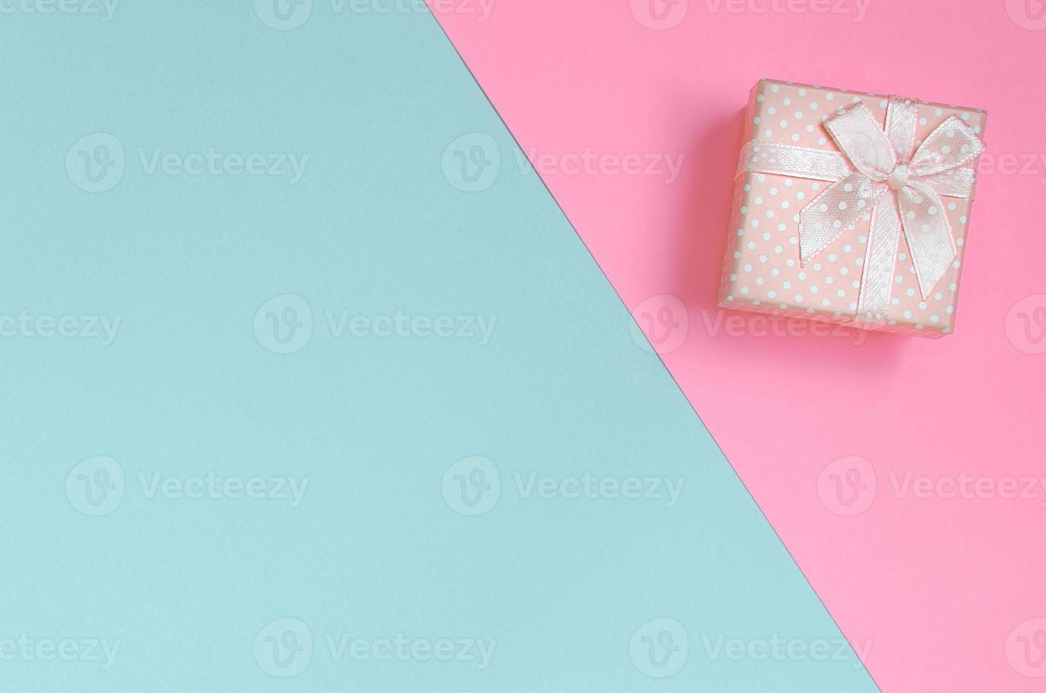 pequena caixa de presente rosa está no fundo de textura de papel de cores azul e rosa pastel de moda em conceito mínimo foto