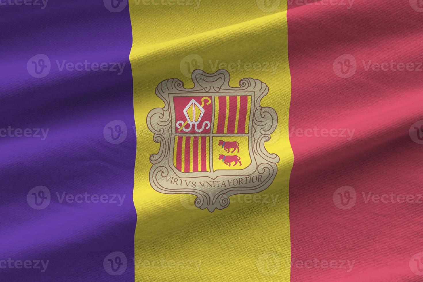 bandeira de andorra com grandes dobras acenando de perto sob a luz do estúdio dentro de casa. os símbolos oficiais e cores no banner foto