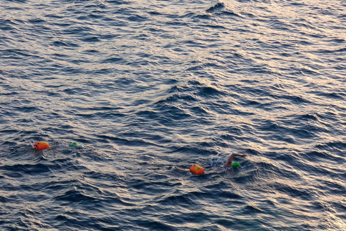 nadador nadando em águas abertas no mar mediterrâneo com uma bóia de segurança foto