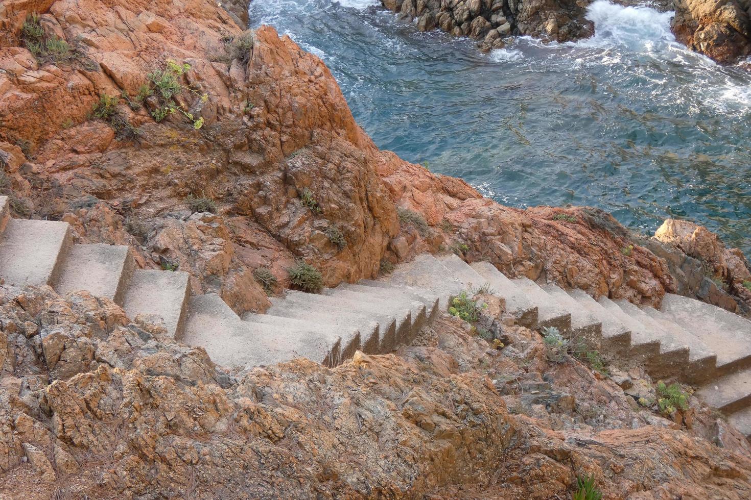escada de pedra esculpida na rocha para descer ao mar foto