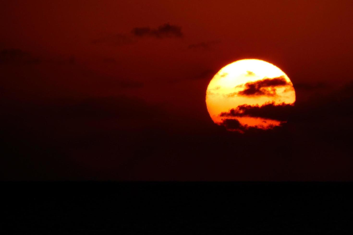 disco solar subindo no horizonte do mar, nascer do sol, amanhecer foto