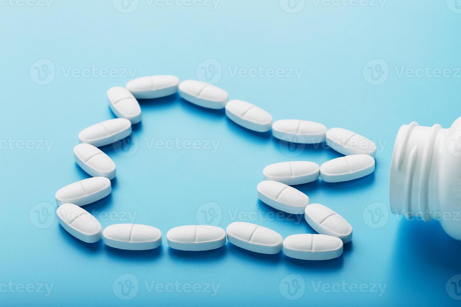 vitaminas com cálcio na forma de um dente derramado de uma jarra branca sobre fundo azul. farmacêutica e odontológica, assistência odontológica foto