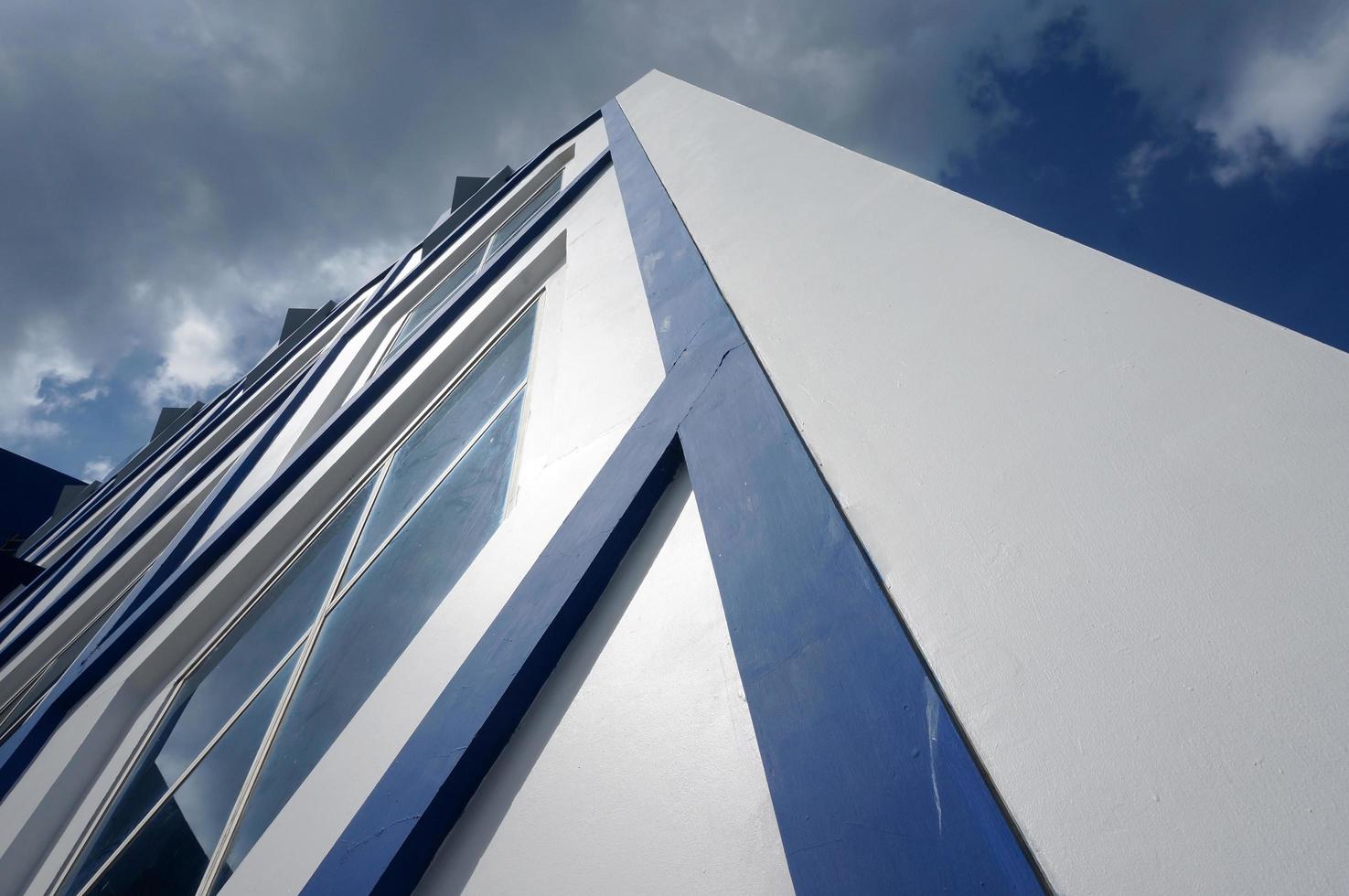 sangatta, leste de kutai, leste de kalimantan, indonésia, 2022 - arquitetura moderna azul e branca com janelas de vidro do pentágono. céu azul e reflexão da nuvem. foto