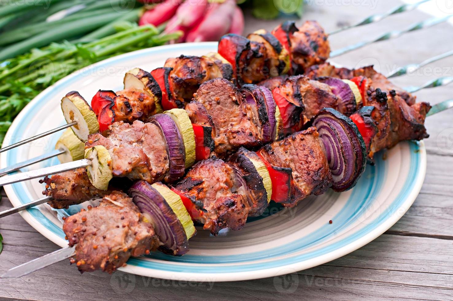 kebabs suculentos e legumes grelhados foto