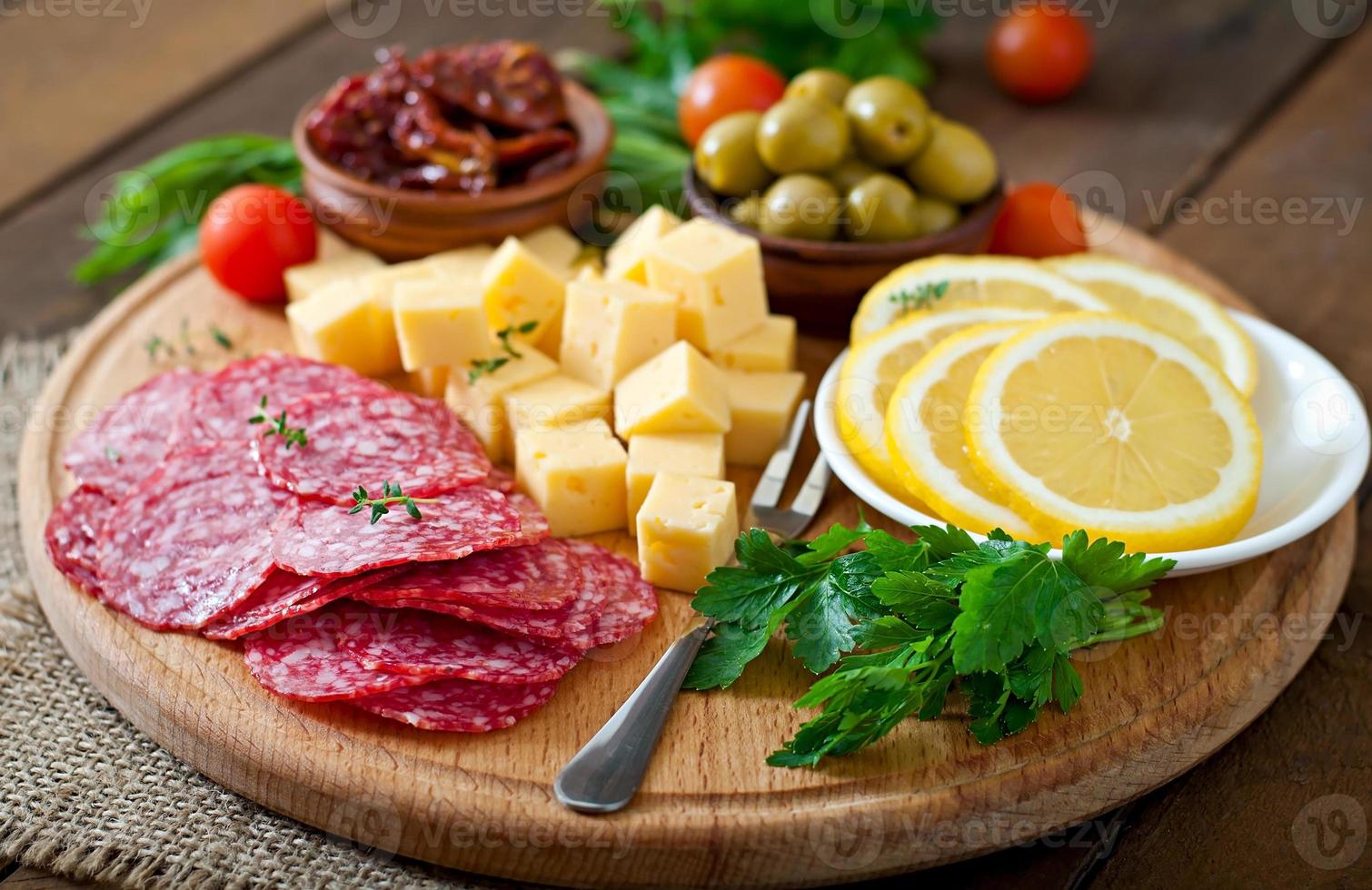 prato de antepasto com salame e queijo em um fundo de madeira foto