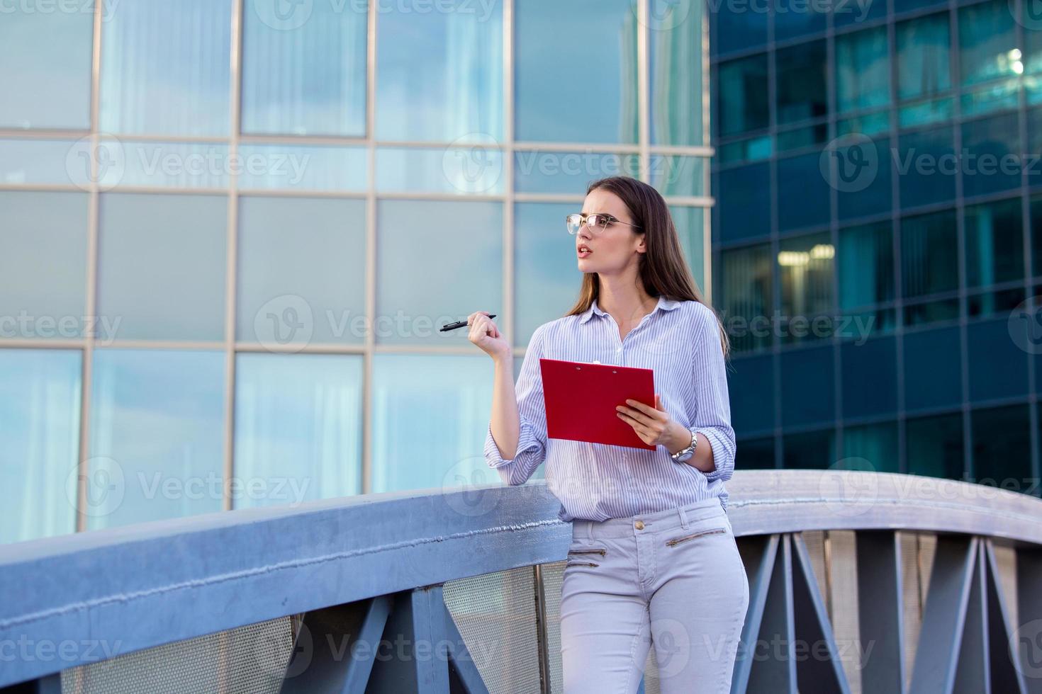 empresária com roupa formal pensando em uma nova oferta de emprego antes de assinar documentos. mulher de negócios segurando a área de transferência. mulher moderna e trabalhadora segurando a prancheta nas mãos, escrevendo em documentos foto