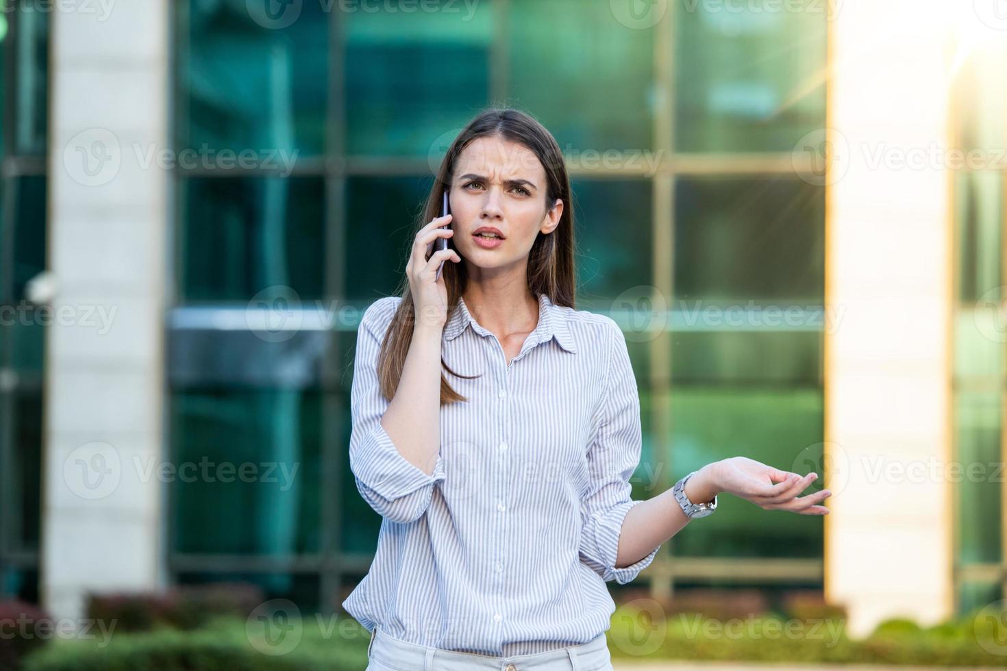 empresária com roupa formal tendo problemas com contratos falando ao telefone. empresária zangada com falha na papelada no local de trabalho, executivos tendo conflito foto