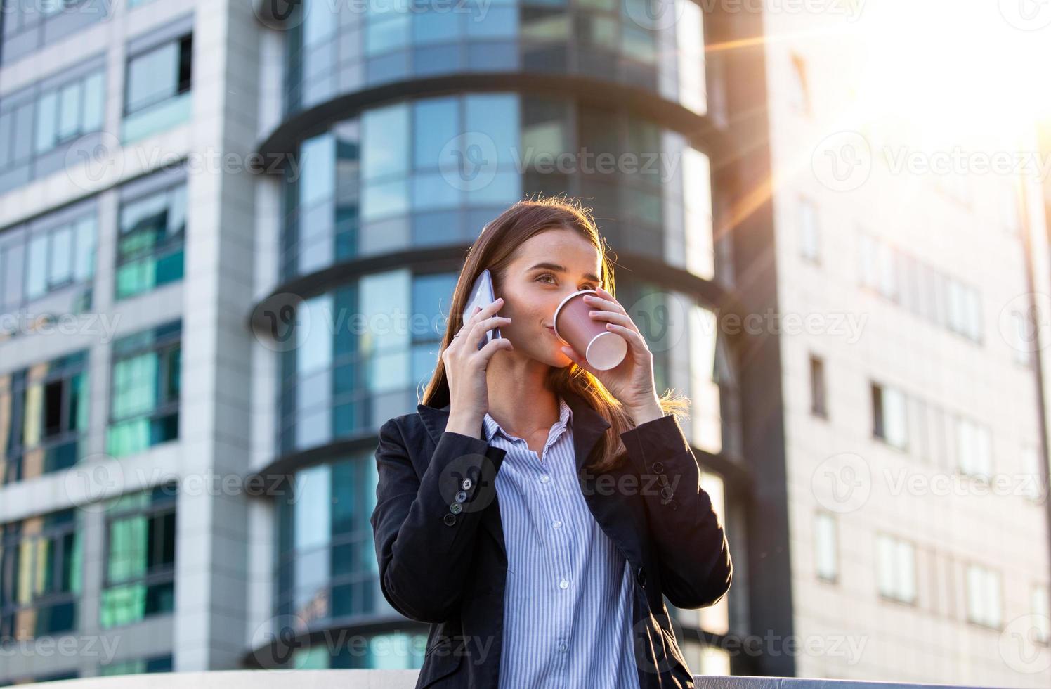 advogada empresária profissional caminhando ao ar livre falando no telefone celular inteligente bebendo café do copo de papel descartável. empresária em seu telefone celular foto