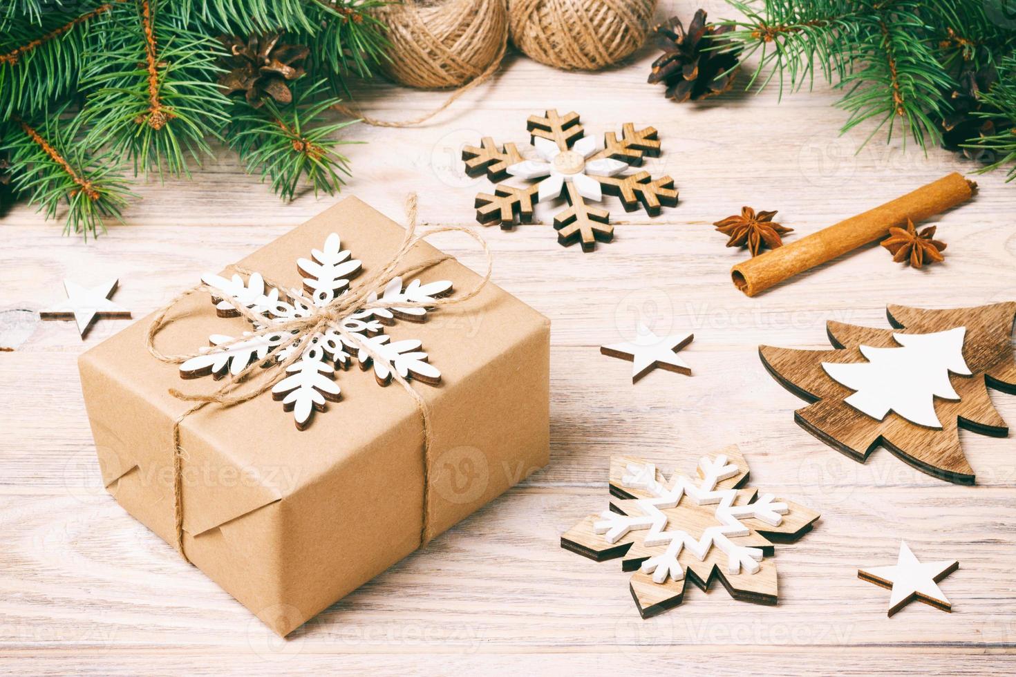 caixa de presente em papel ofício com decoração de natal, corda de barbante, fundo do conceito, vista superior na superfície da mesa de madeira. enfeites de natal e presentes fronteira com flocos de neve e estrelas. tonificado foto