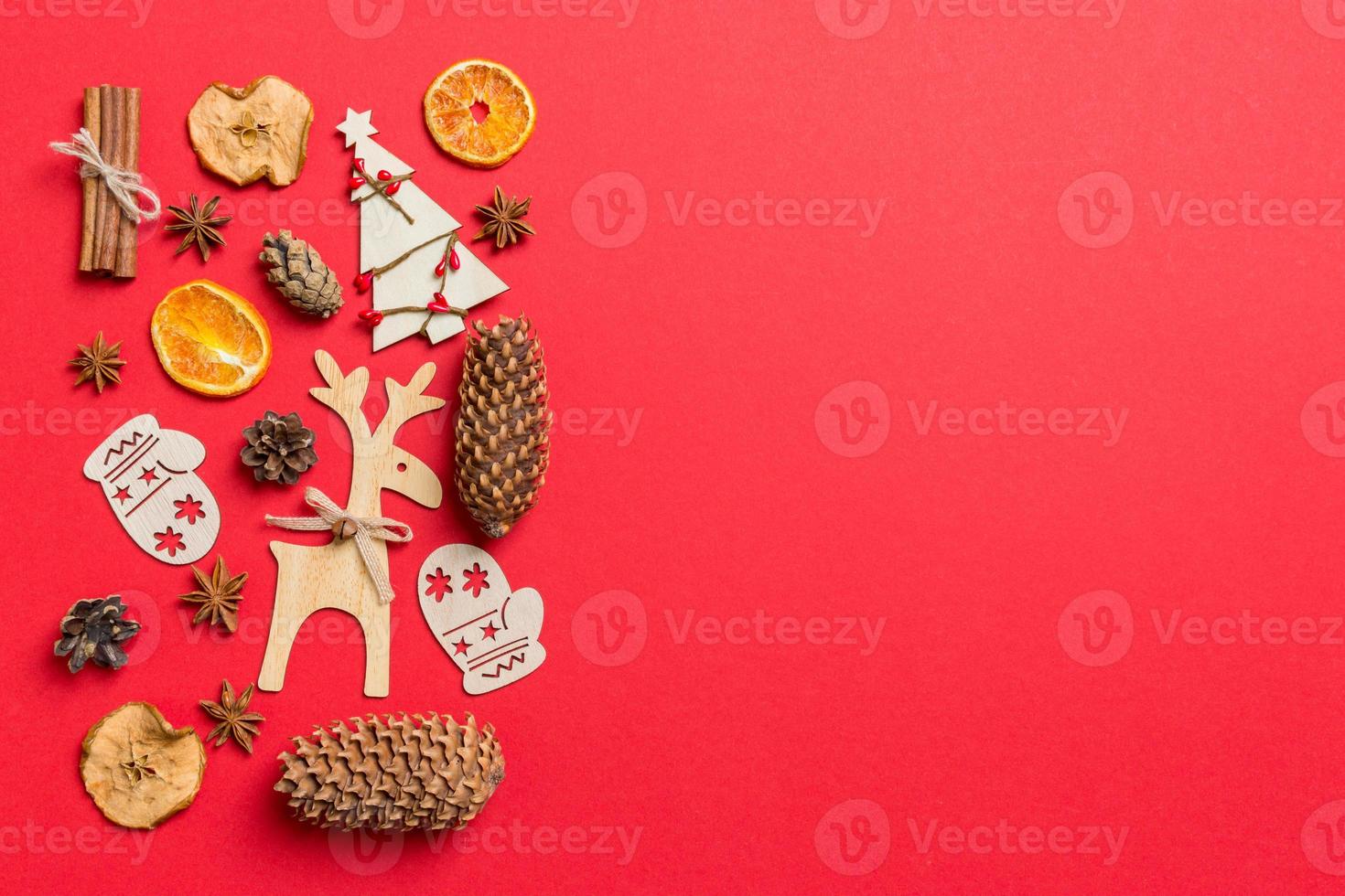 vista superior do fundo vermelho decorado com brinquedos festivos e renas de símbolos de natal e árvores de ano novo. conceito de férias com espaço de cópia foto