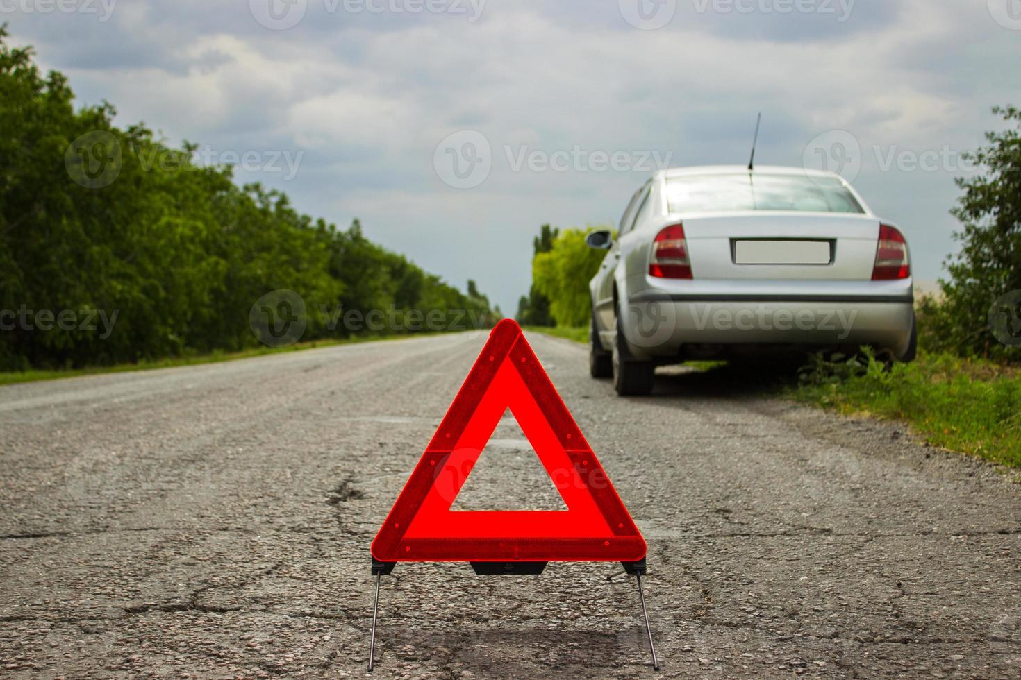 triângulo vermelho de um carro na estrada. triângulo de advertência do carro na estrada contra a cidade à noite. avaria do carro em mau tempo. foto