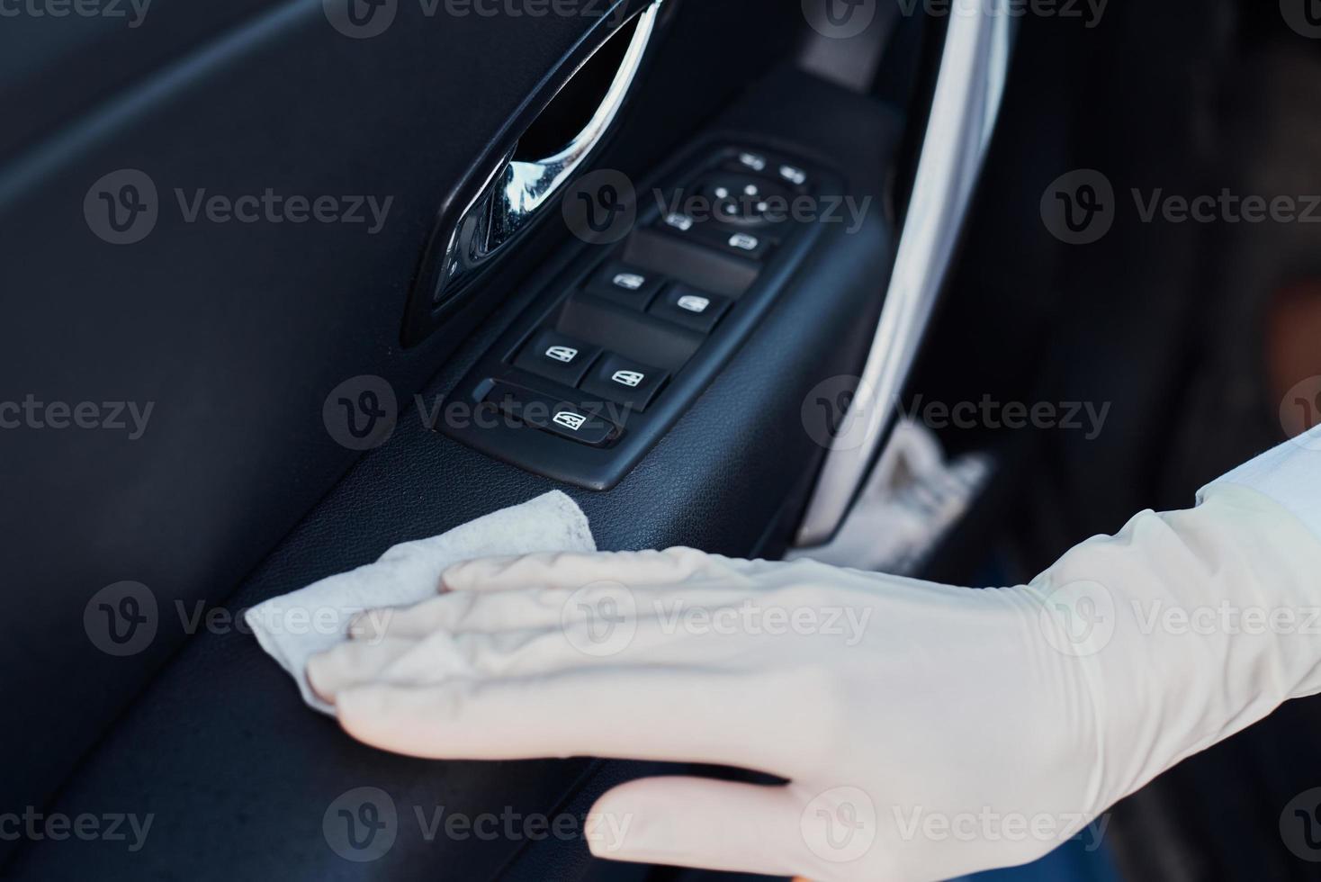 interior do carro de limpeza de mulher. mão com um pano antibacteriano desinfetar carro foto