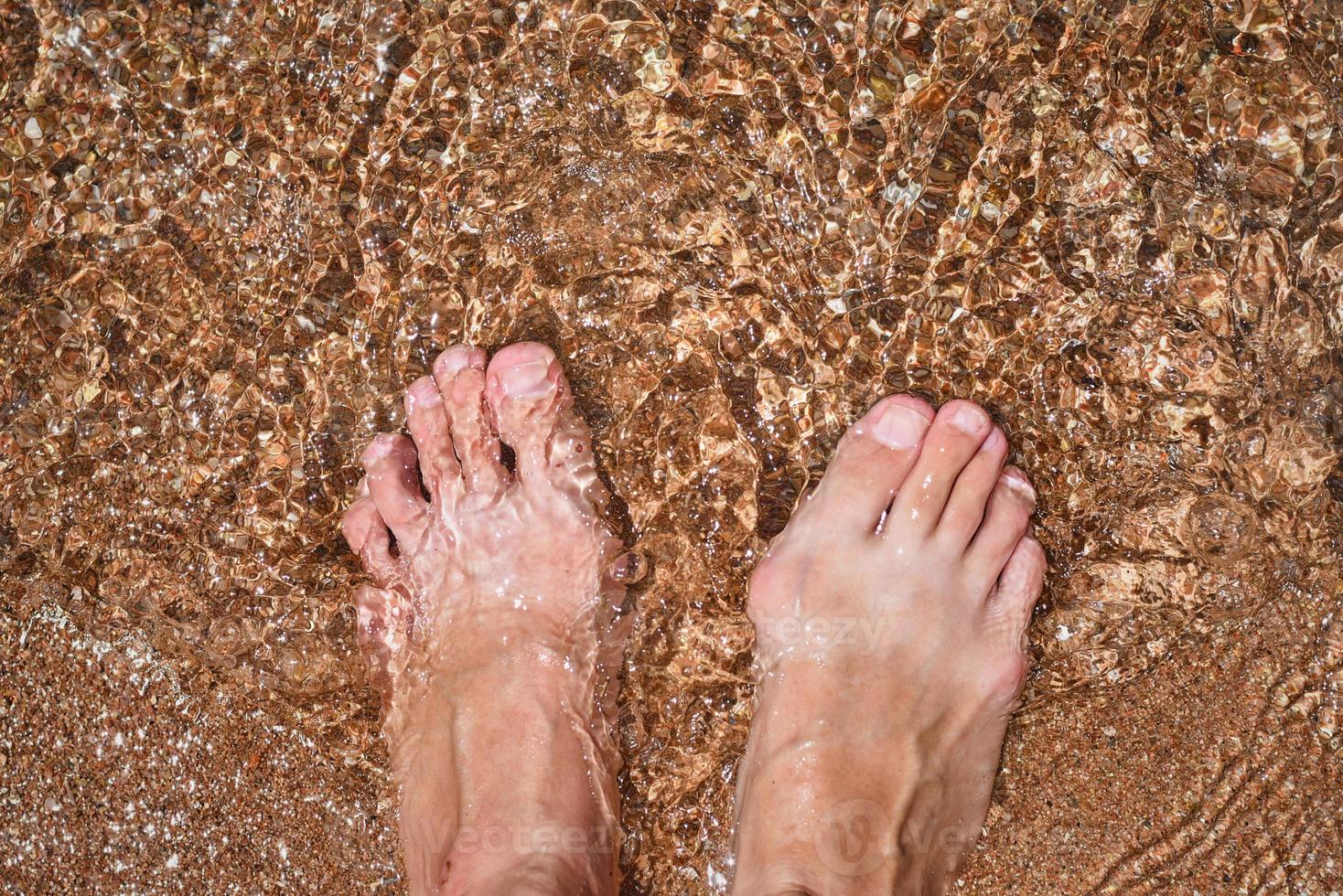 close-up das pernas descalças na água, vista de cima foto