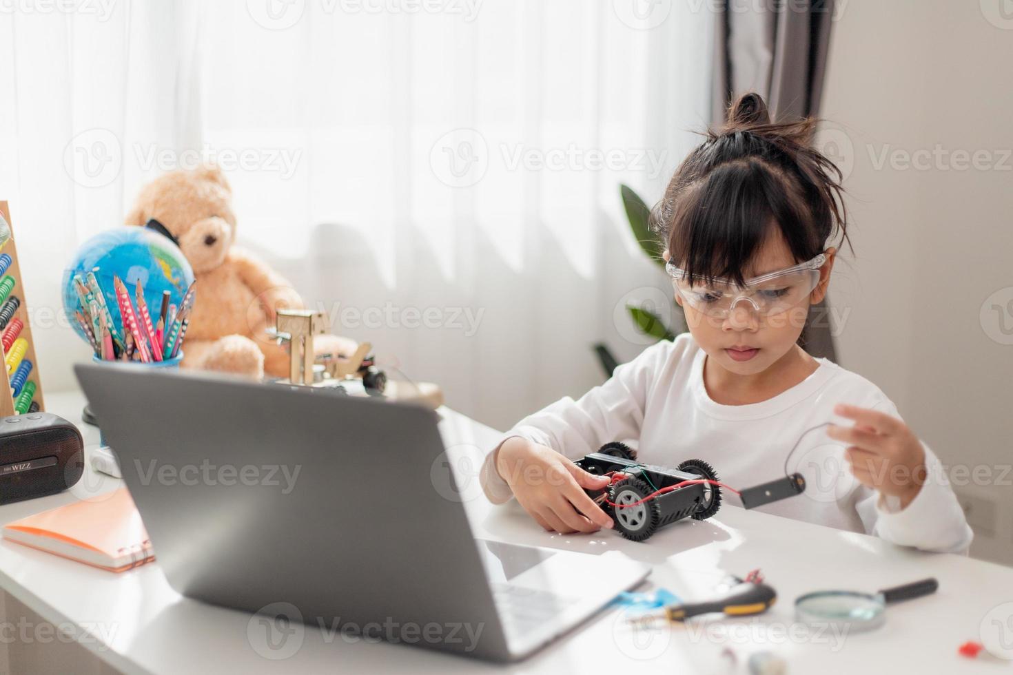 os alunos da ásia aprendem em casa na codificação de carros robóticos e cabos de placa eletrônica em haste, vapor, código de computador de tecnologia de ciência de engenharia matemática em robótica para o conceito de crianças. foto