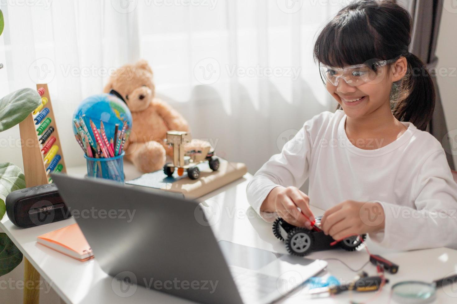 os alunos da ásia aprendem em casa na codificação de carros robóticos e cabos de placa eletrônica em haste, vapor, código de computador de tecnologia de ciência de engenharia matemática em robótica para o conceito de crianças. foto