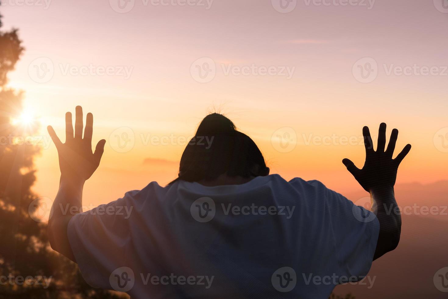 a fé da oração espiritual do conceito cristão entrega a luz do sol com um belo nascer do sol ou fundo do pôr do sol desfocado. cristãos que acreditam, fé na oração matinal de Deus. foto