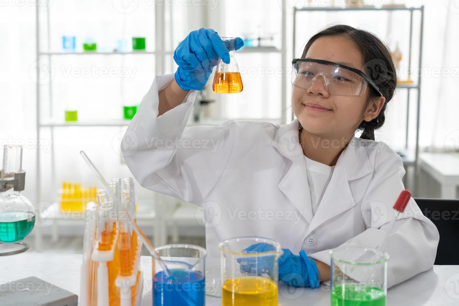 retrato de uma jovem garota aisan aprendendo ciência e usando microscópio em laboratório foto