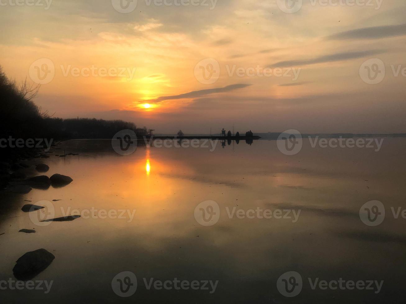 lindo pôr do sol vermelho sobre o horizonte da água no rio, mar, oceano, lago foto