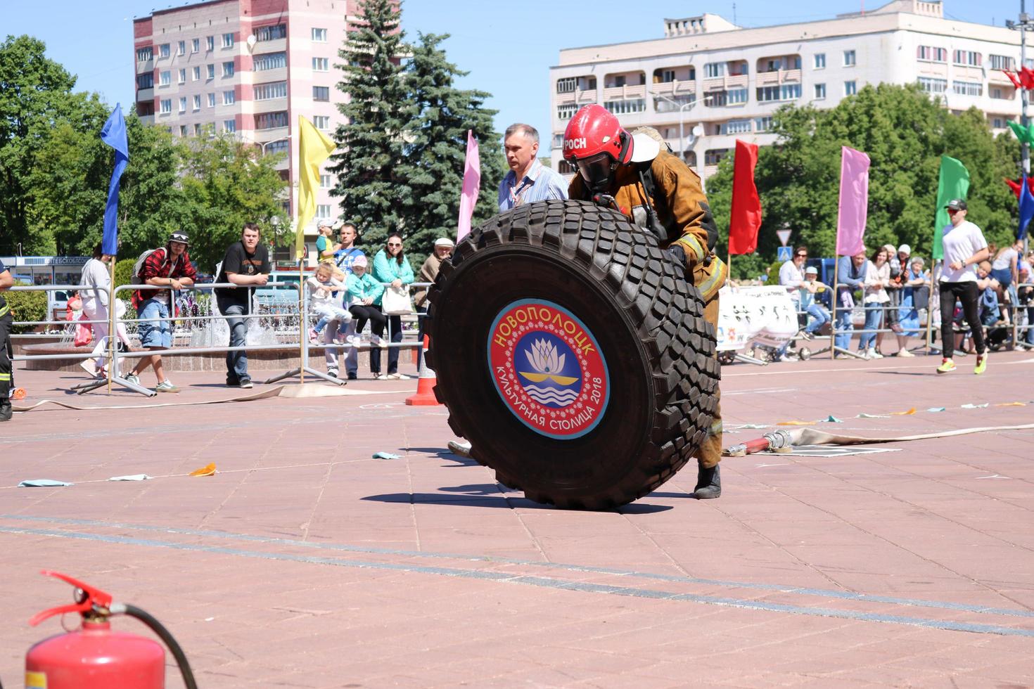 um bombeiro em um traje à prova de fogo e um capacete corre e gira uma grande roda de borracha em uma competição de combate a incêndio, bielorrússia, minsk, 08.08.2018 foto