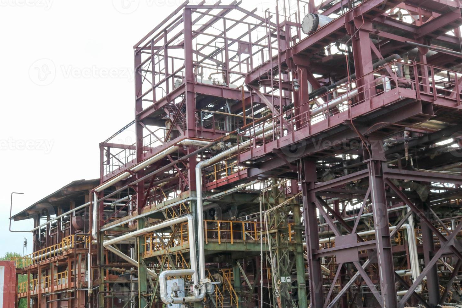 um grande cavalete de tubulação de metal de ferro com tubos e fios elétricos e equipamentos na refinaria petroquímica refinaria industrial foto