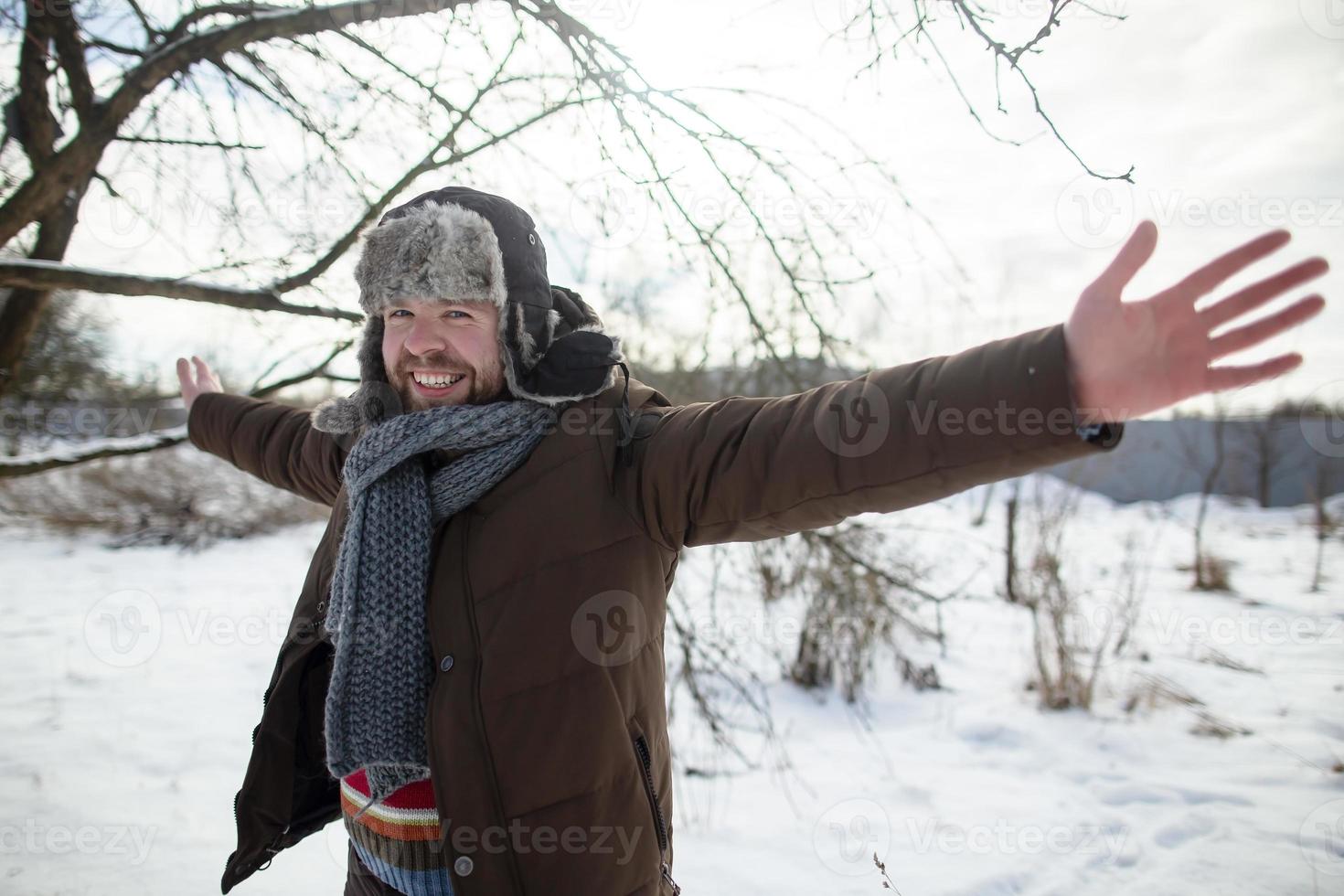 homem feliz e sorridente abre os braços para os lados e olha para a câmera, ele está feliz por andar em um parque coberto de neve, em um dia de primavera. foto