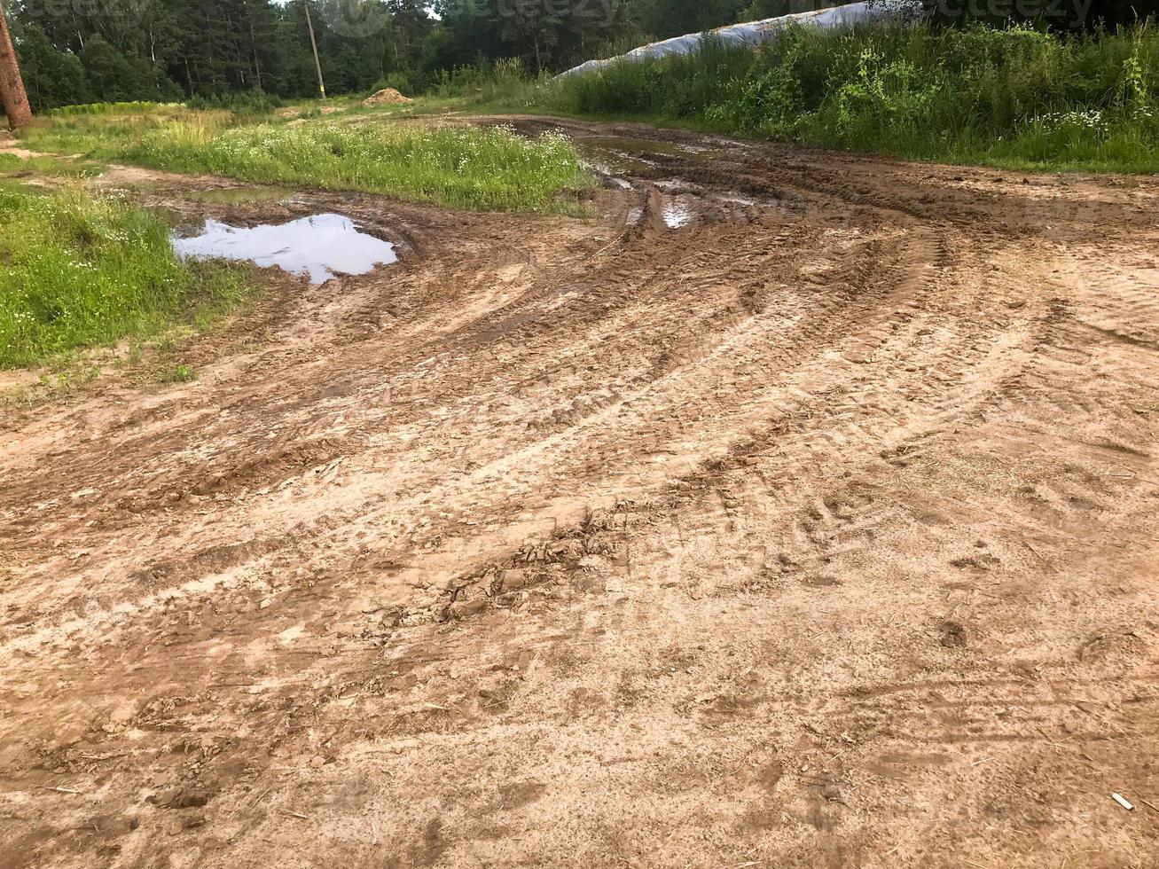 textura de uma estrada de terra suja e ruim com poças e lama de secagem de argila com rachaduras e sulcos. fora da estrada. o fundo foto
