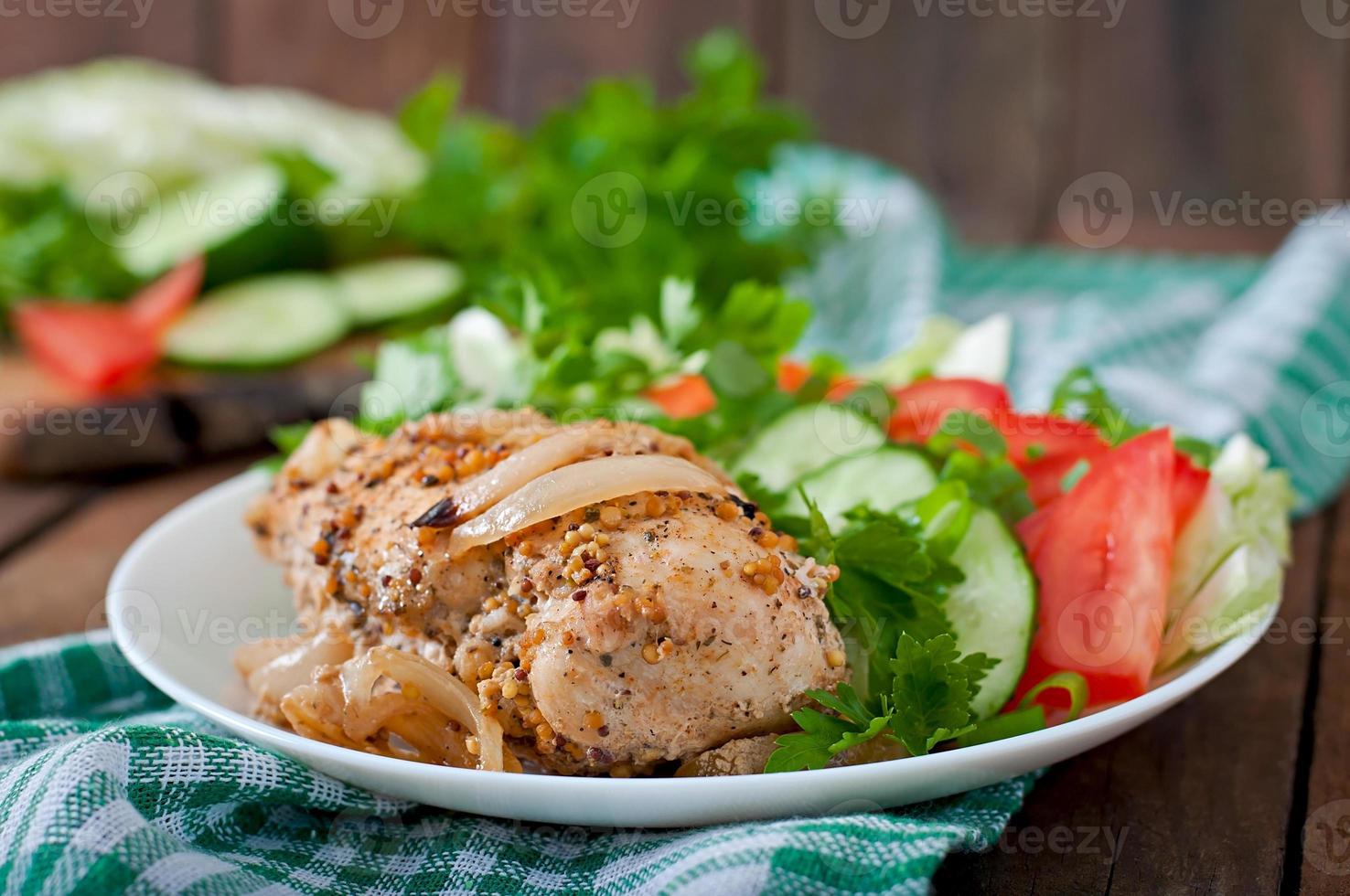peito de frango assado e legumes frescos no prato sobre um fundo de madeira foto