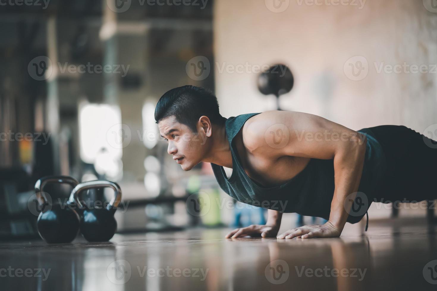 esportista de ajuste asiático fazendo flexão de exercício no piso de madeira no ginásio de fitness. esporte homem exercício no centro esportivo. conceito de ginásio de fitness esporte. foto