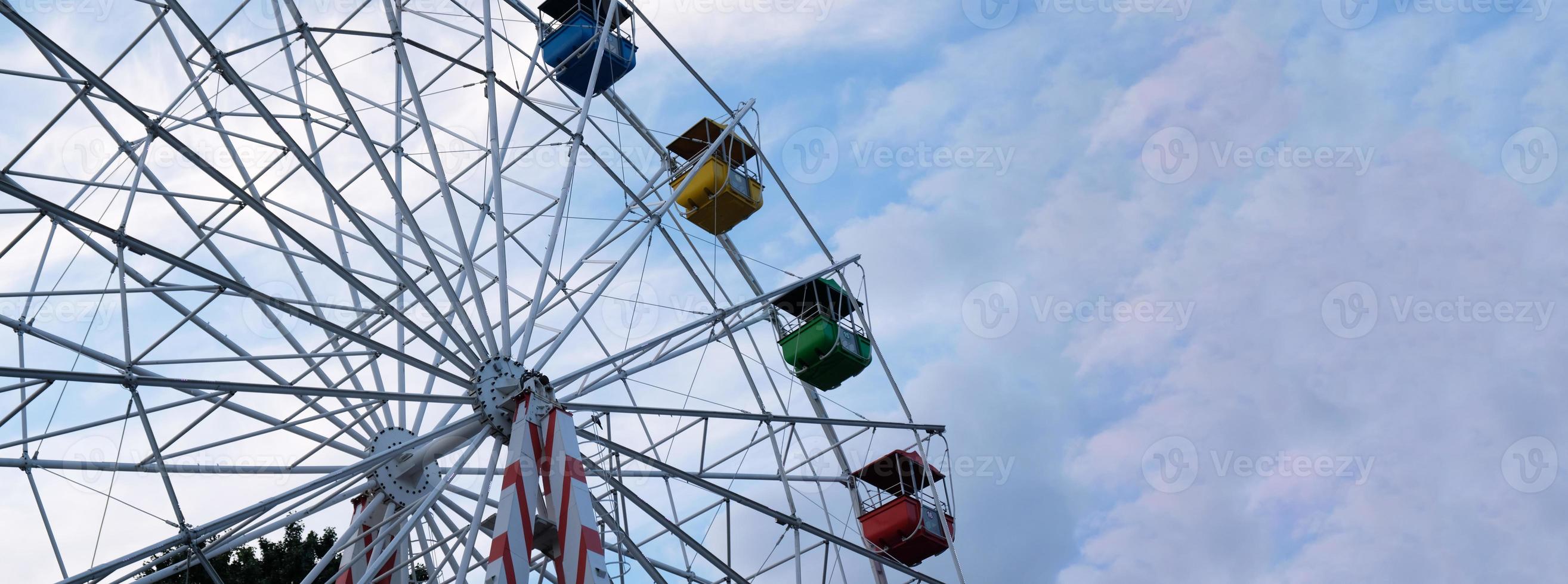 rodas gigantes coloridas no parque de diversões em um fundo de céu azul com nuvens. imagem tonificada. vista de baixo foto