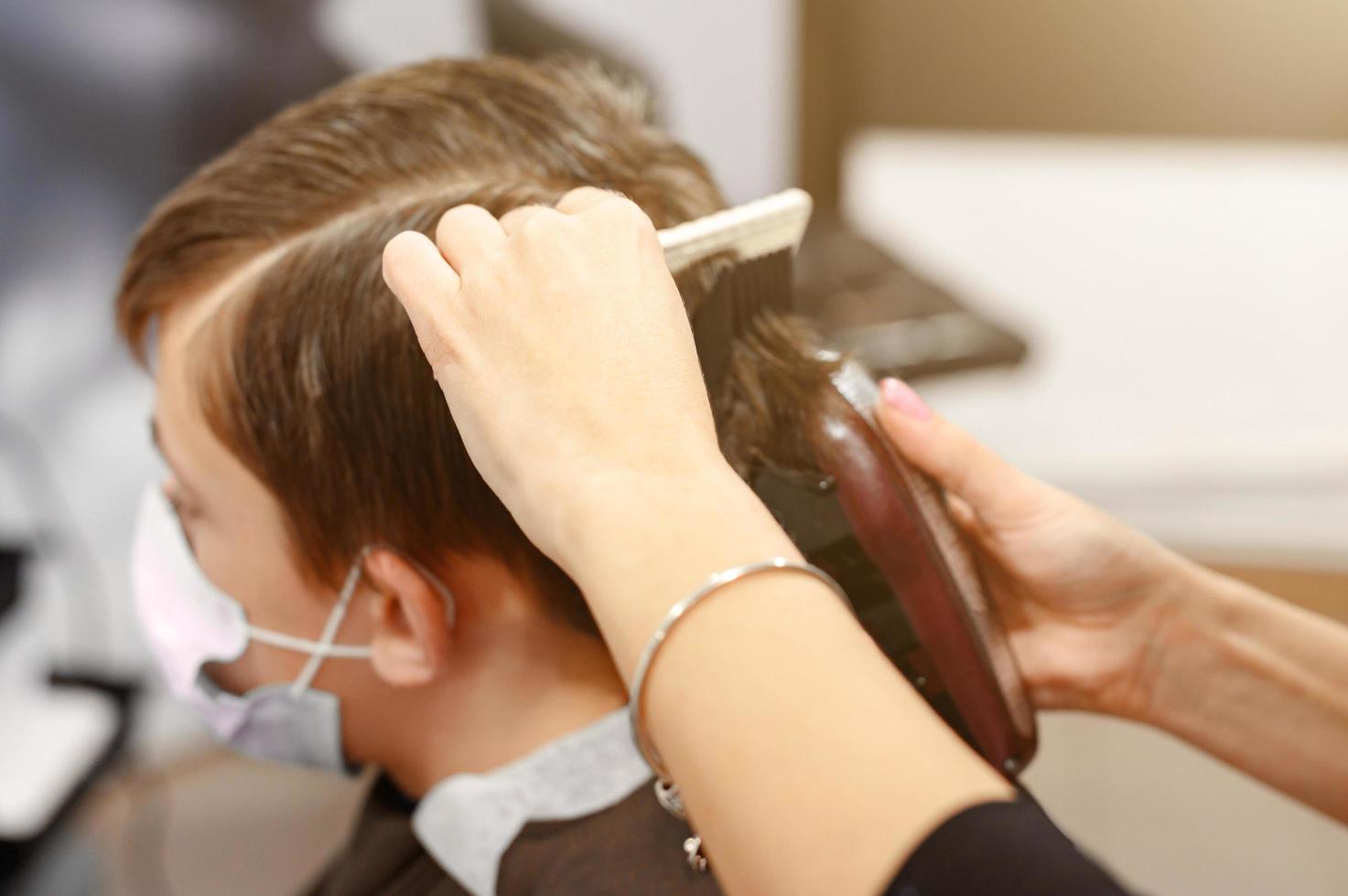 um adolescente em um salão de beleza corta o cabelo, um cabeleireiro corta o cabelo de um adolescente. foto