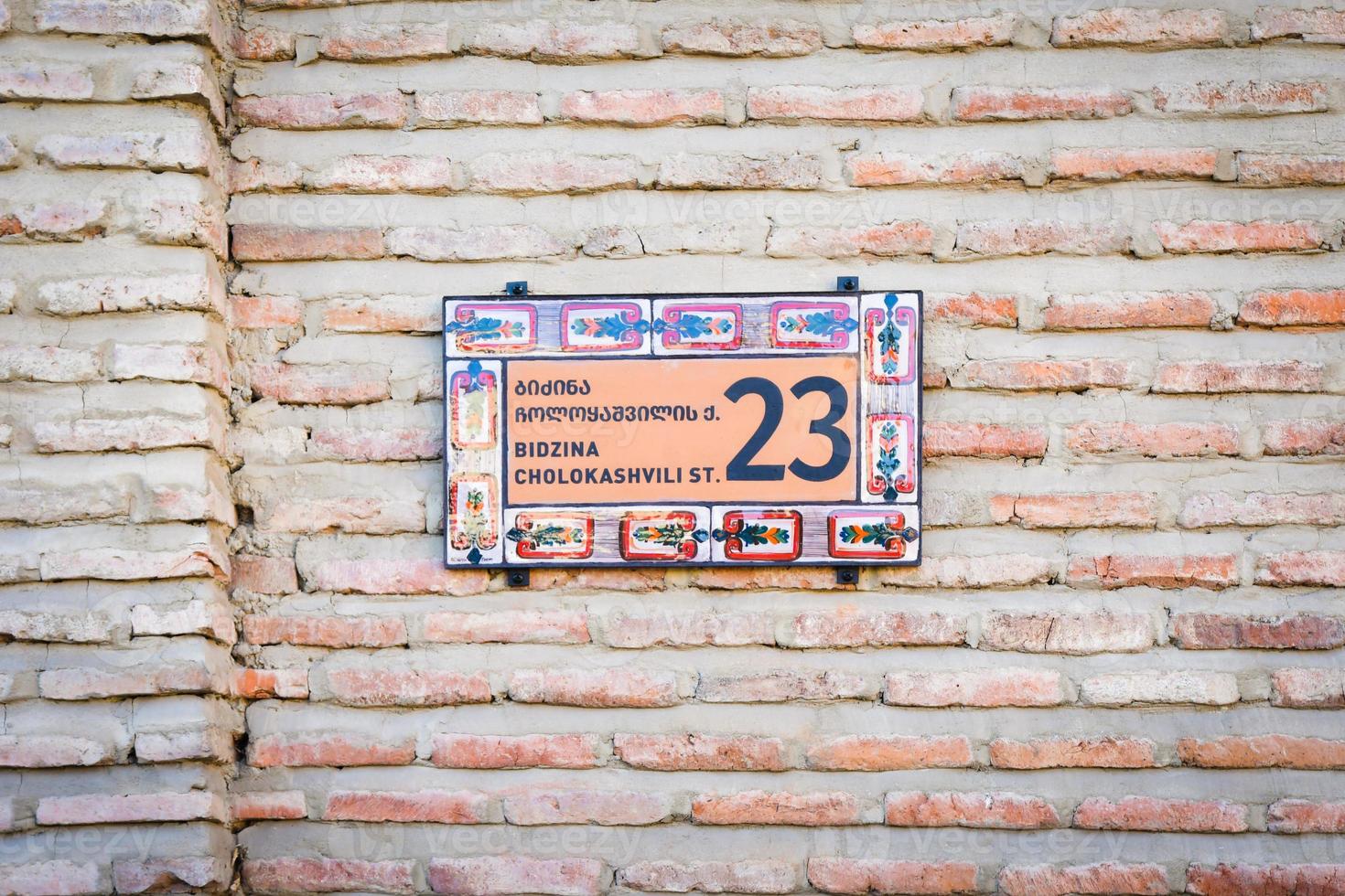 parede de tijolos com elegante número de casa ornamental e sinal de nome de rua na cidade velha telavi. rua bidzina cholokashvili de casas históricas antigas patrimônio georgiano em kakheti foto