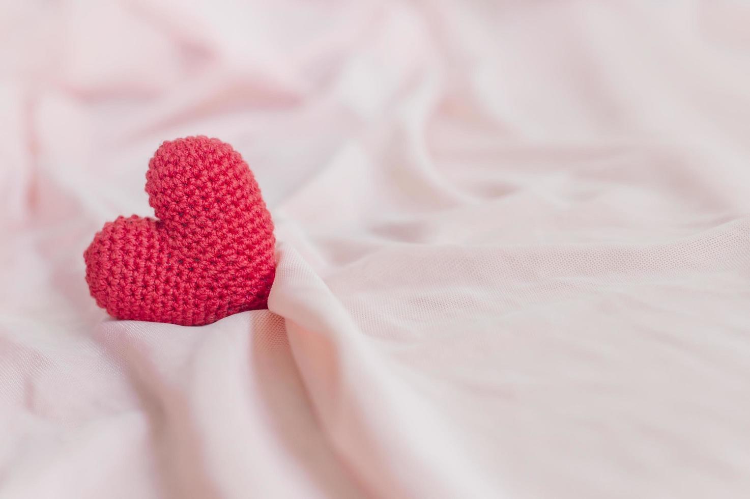 close-up de coração vermelho feito à mão em tecido rosa para dia dos namorados ou plano de fundo do casamento foto