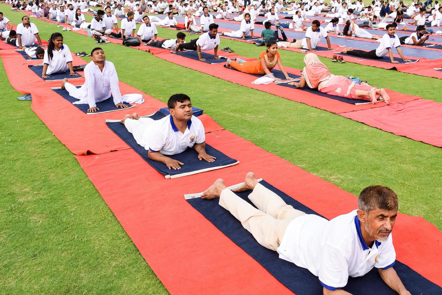 nova delhi, índia, 21 de junho de 2022 - sessão de exercícios de ioga em grupo para pessoas no complexo esportivo yamuna em delhi no dia internacional de ioga, grande grupo de adultos participando de aula de ioga no estádio de críquete foto