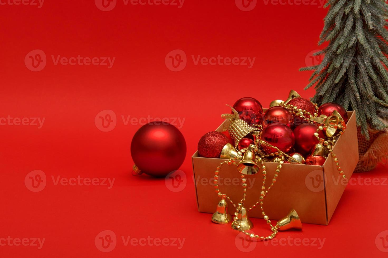 árvore de natal, brinquedos de ano novo em uma caixa em um fundo vermelho com espaço de cópia, natal, feriado foto